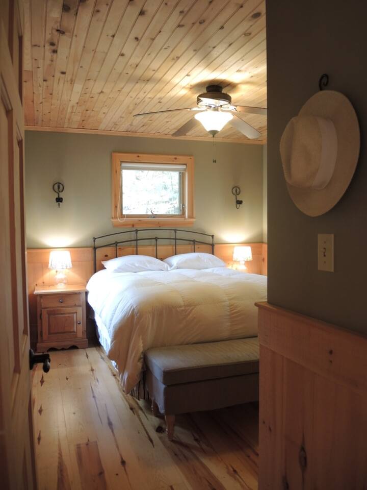 マスターベッドルーム／クイーンサイズベッド（枕と羽毛布団付き） ／ランプ付きナイトテーブル／パッド入りベンチ（収納付き）