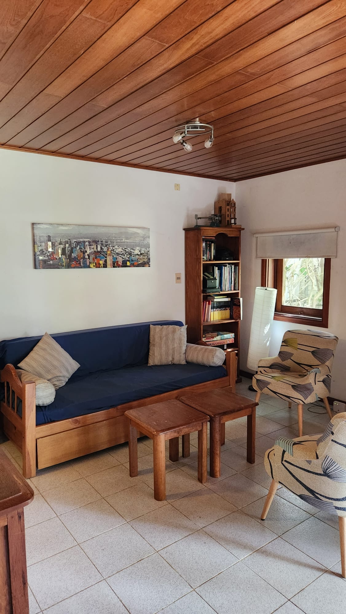 Foto del estar de la casa, el cual cuenta con un sillón cama y dos modernas butacas.