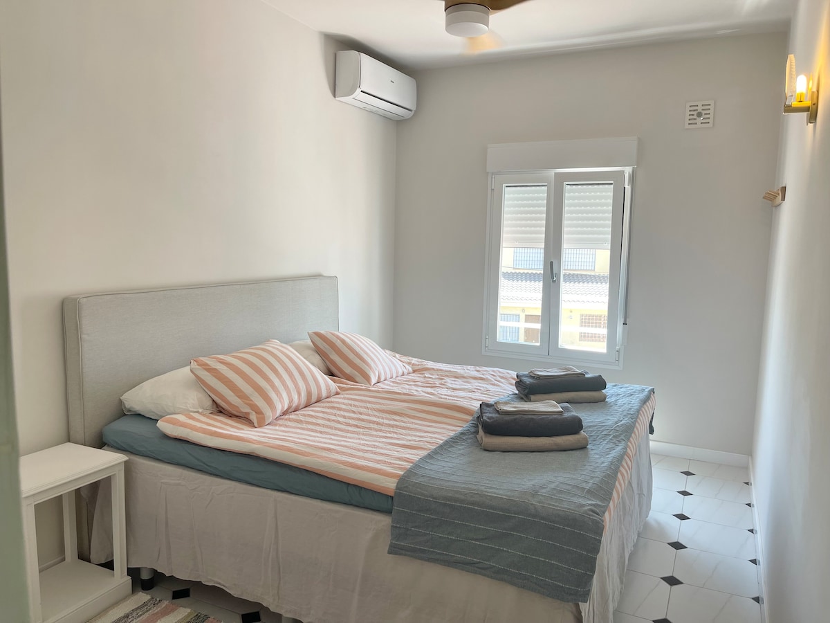Dormitorio 1 con cama matrimonial de 180 cm y armario, aire acondicionado y ventilador de techo
