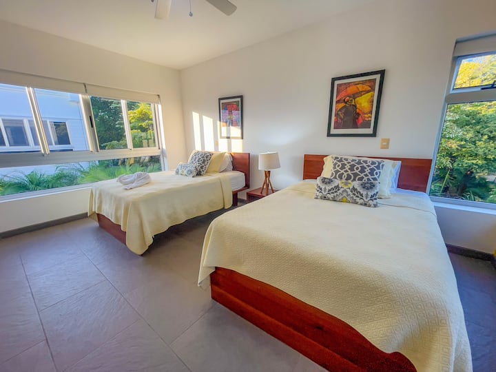 Schlafzimmer Nummer 2 mit zwei großen Betten und schönem Blick auf die üppigen Gärten des Hauses Bella Vista