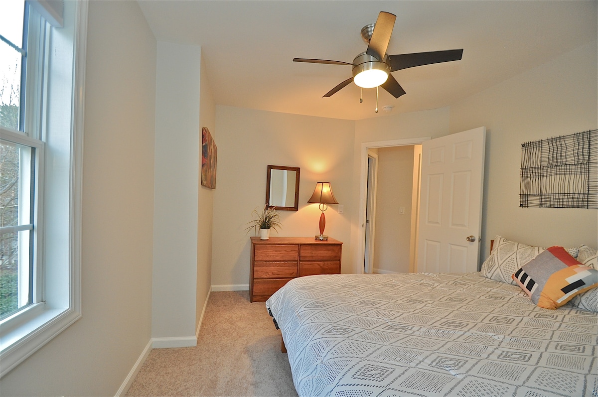 Gastenkamer met queensize bed met een nieuwer premium matras, kast, plafondventilator en raam met uitzicht op de voorkant van het huis. (uitzicht 1)