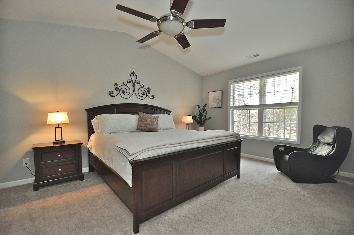 Ruime hoofdslaapkamer met kingsize bed met een nieuwer premium matras, plafondventilator, massagestoel en raam met uitzicht op het terrein achter. Er is een grote hoofdbadkamer en een inloopkast naast deze slaapkamer. (weergave 1)