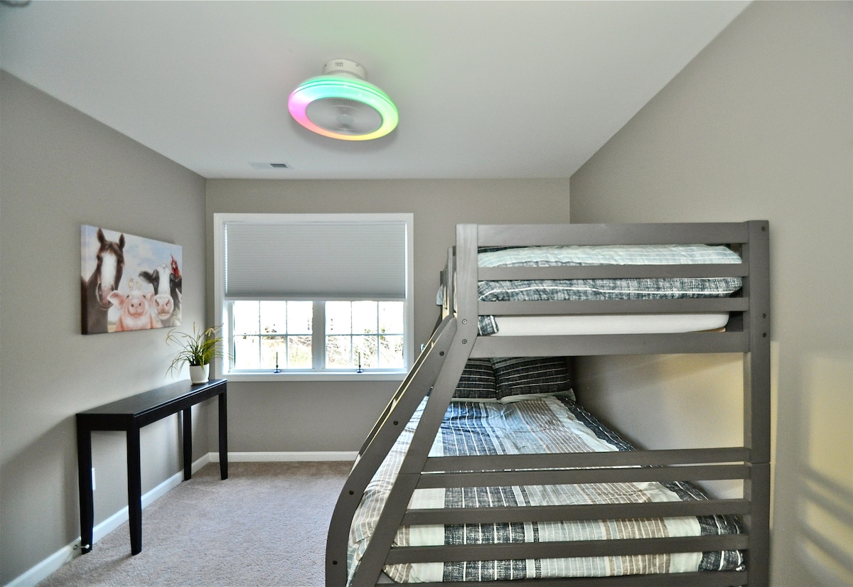 Gastenkamer met stapelbed met een volledig nieuwer premium matras en een nieuwere premium matras met twee eenpersoonsbedden, plafondventilator/lamp, kast en raam met uitzicht op de voorkant van het huis. (uitzicht 1)