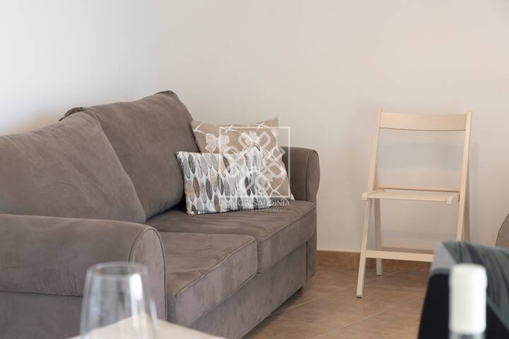 Detalj dnevnog boravka s kaučem u apartmanu u Castelsardu s pogledom na more i privatnim balkonom