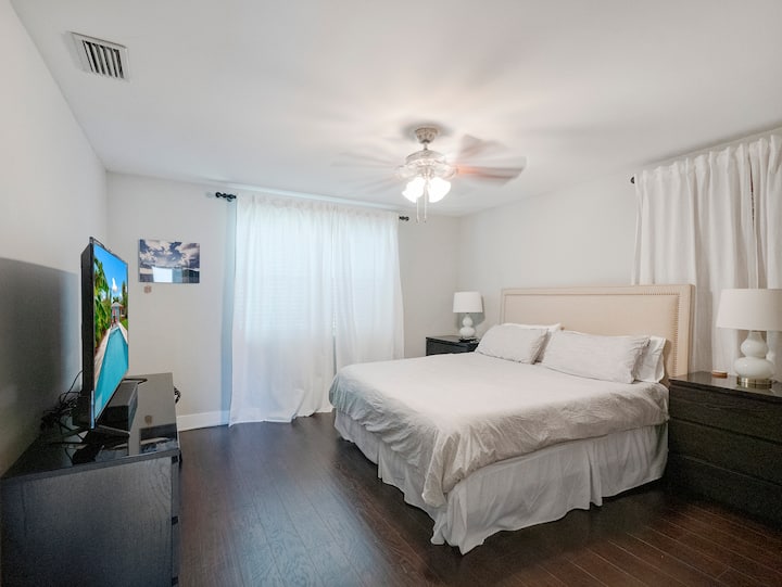 King sized bed, dresser, nightstands, closet, and TV in this spacious bedroom