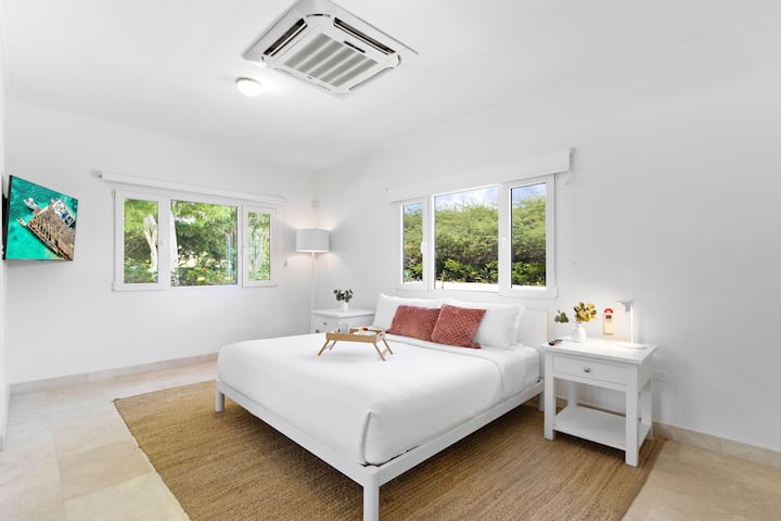 Dormitorio 2 | Experimenta el epítome de la comodidad en uno de los dormitorios de Boca Beach House. Este lujoso santuario cuenta con baño privado, TV para el entretenimiento y un espacioso vestidor.