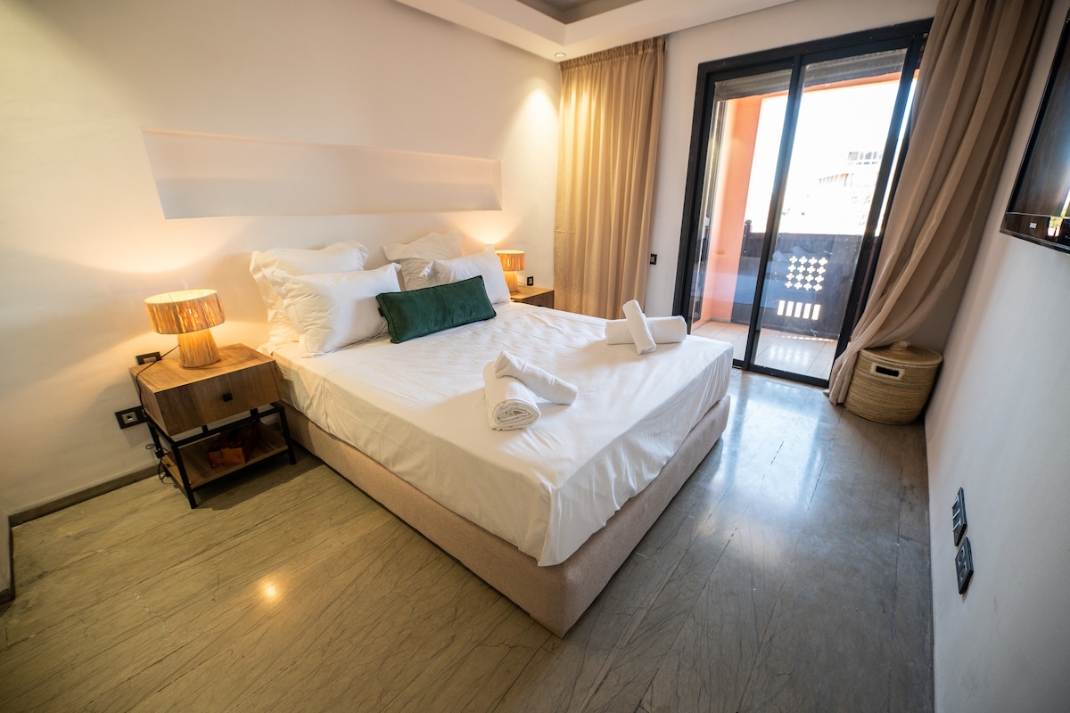 ห้องนอนสวีทขนาดควีนไซส์พร้อมฝักบัวอาบน้ำเปิดอยู่บนระเบียง