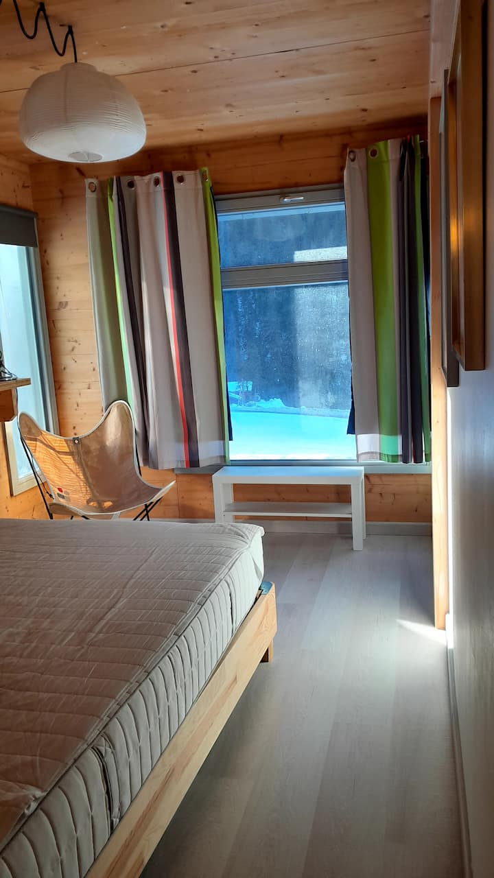 Suite matrimoniale - vista dall'ingresso della camera da letto sul letto con vista verso l'esterno e la neve sul vetro di fondo.