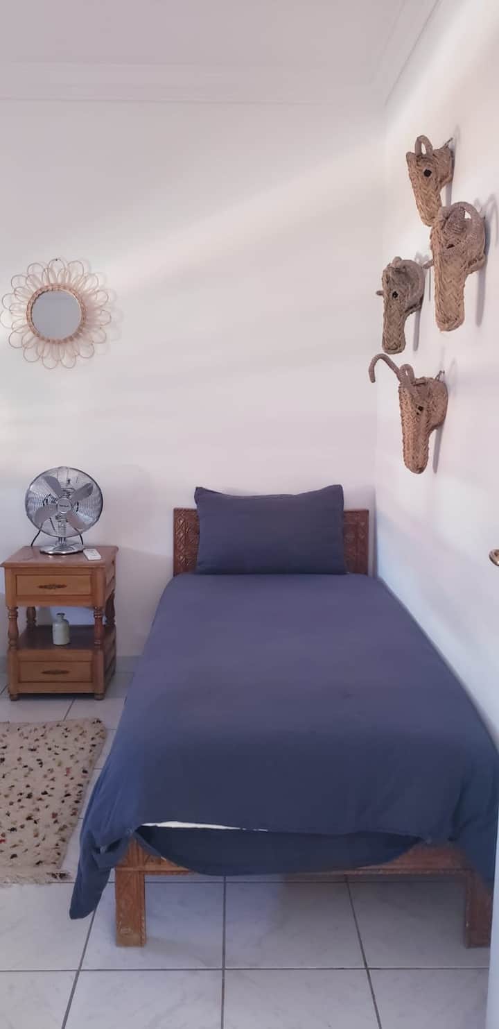 Chambre lumineuse avec deux lits simples, idéale pour amis ou enfants, offrant calme et confort pour un séjour agréable.