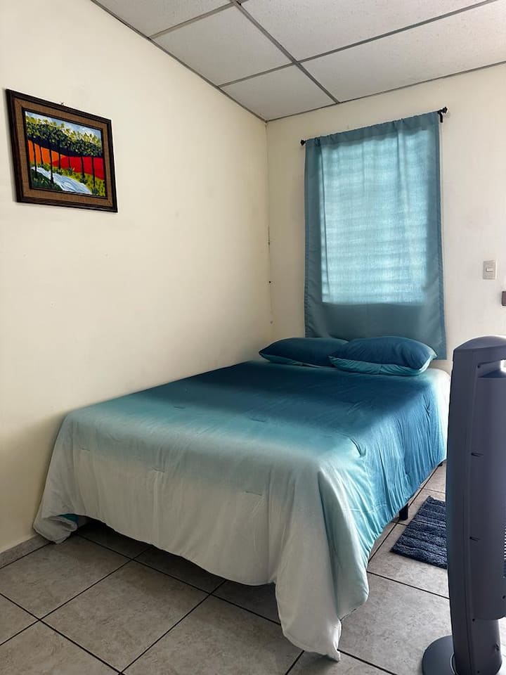 Slaapkamer met bed voor twee personen en voetstukventilator 