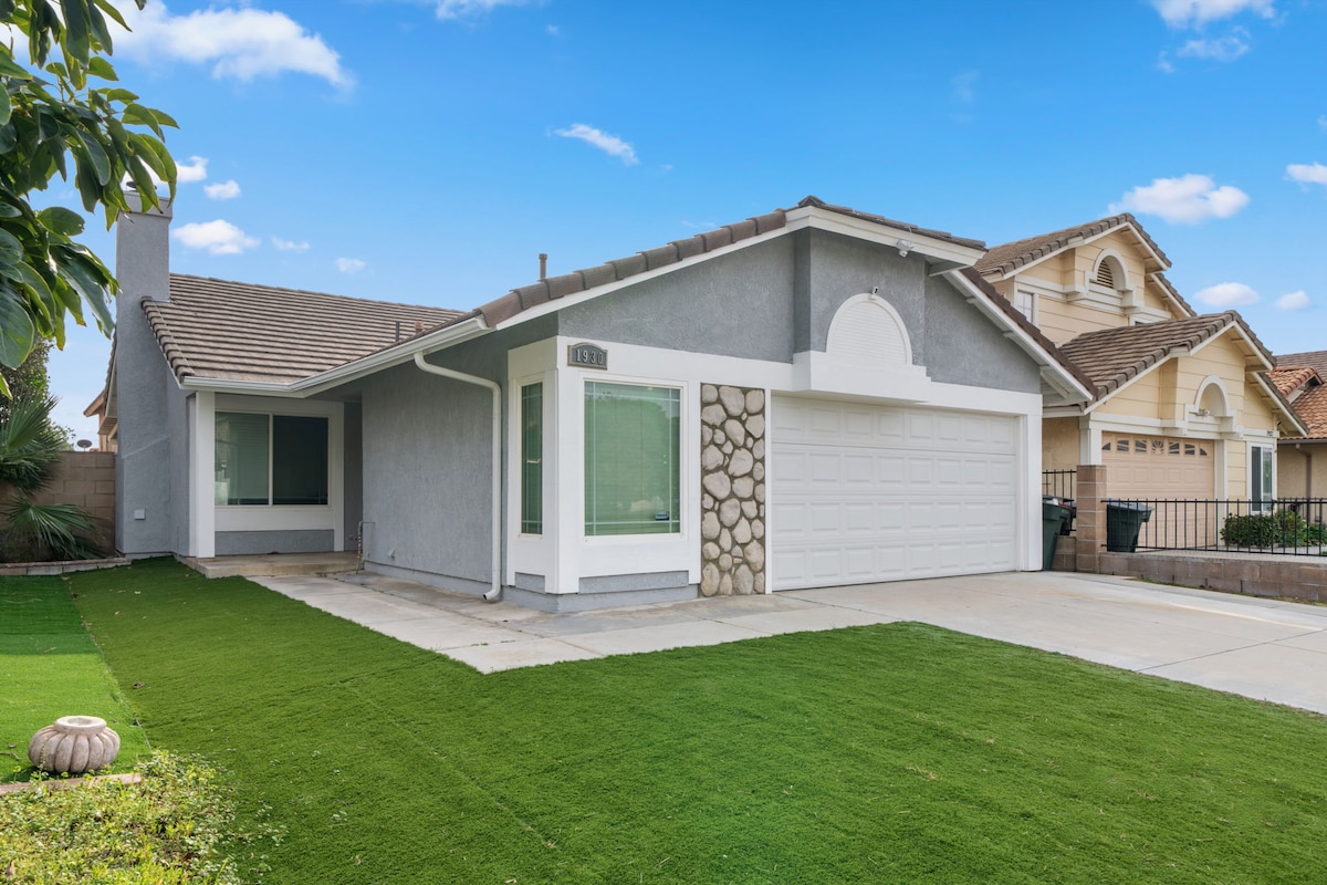 The exterior of the bungalow features a well-maintained lawn and a modern facade. A stone accent wall complements the garage, while large windows allow natural light into the open layout. The inviting entrance prepares guests for a comfortable stay.