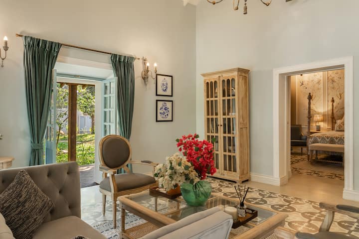 ✨A graceful lounge corner with garden views, antique wood cabinetry, and soft-toned furnishings that open into a charming four-poster bedroom✨