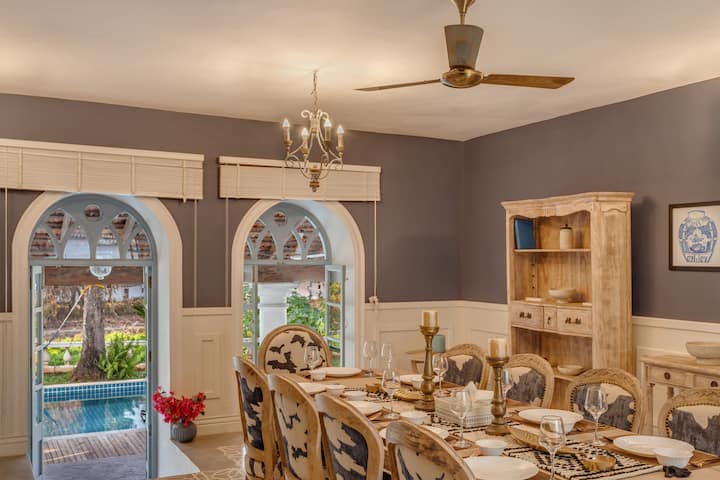 ✨A refined dining room where colonial charm meets modern grace-arched windows, carved woodwork and an open view of the pool for sunlit gatherings✨