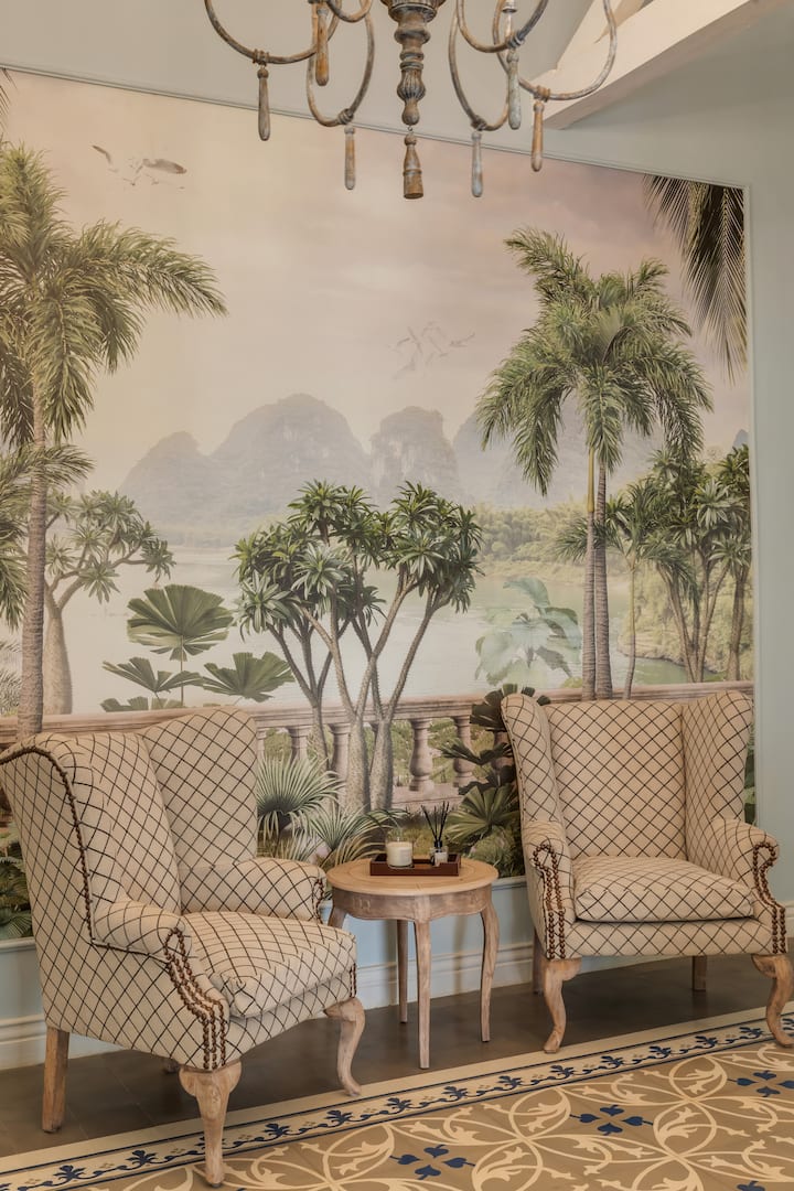 ✨This elegant nook, framed by tropical mural art and vintage wingback chairs, invites quiet moments with a cup of coffee or a good book✨