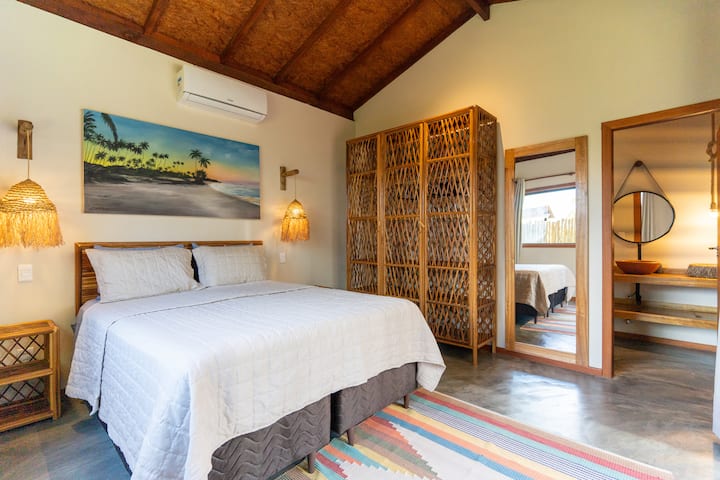 Cómoda suite en Barra Grande, península de Maraú, Bahía, con una cama grande, aire acondicionado y decoración tropical. Ambiente tranquilo, bien iluminado e integrado con la naturaleza, ideal para noches de descanso después de un día de playa