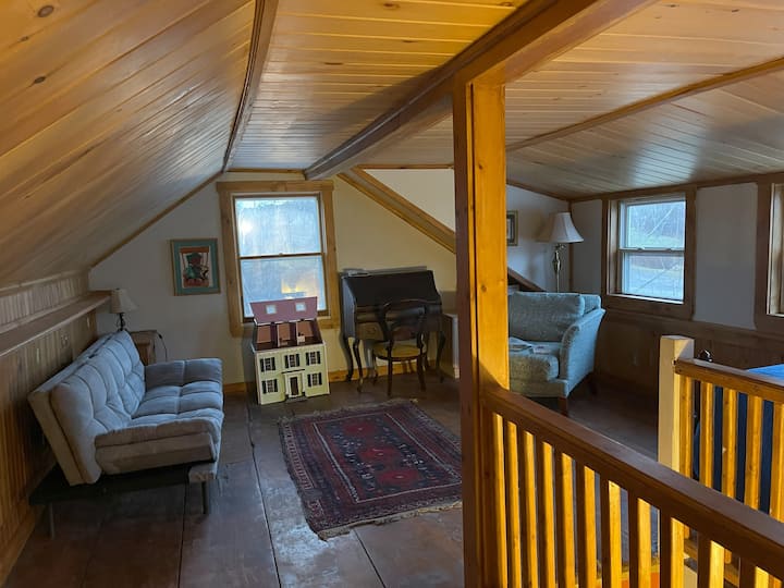 La sala de estar 2 es un espacioso loft abierto en la planta superior con una puerta que se puede cerrar desde la planta baja. Hay una cama tamaño queen, una cama individual y un sofá cama, así como un espacio de trabajo de oficina, una pequeña zona de juegos para niños y un televisor. 