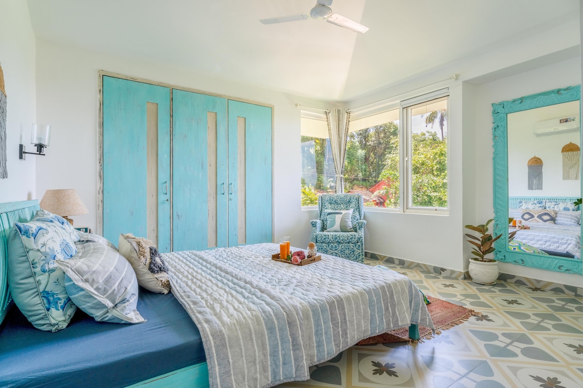 Dormitorio con cama tamaño queen, espejo de cuerpo entero, mecedora, armario de almacenamiento, grandes ventanales y baño privado. 