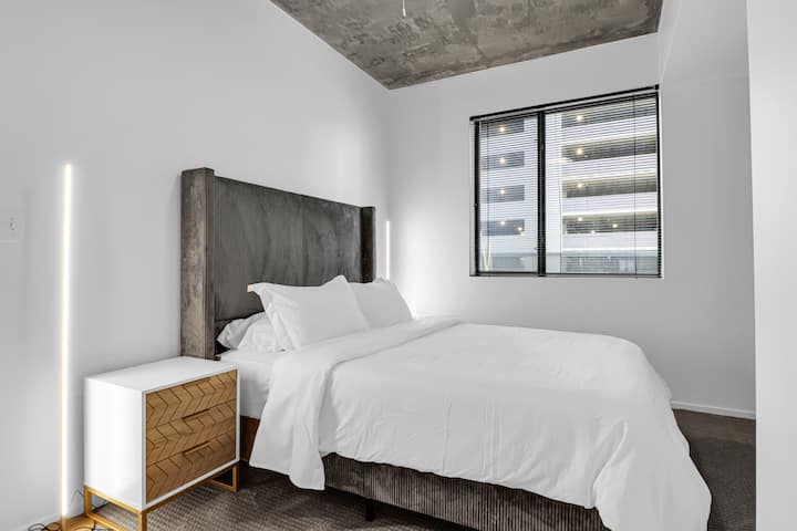 غرفة نوم أنيقة تتميز بسرير بحجم كوين وبياضات فاخرة وألوان مهدئة وإضاءة ناعمة لملاذك الخاص لقضاء ليالٍ مريحة في قلب وسط مدينة فينيكس.