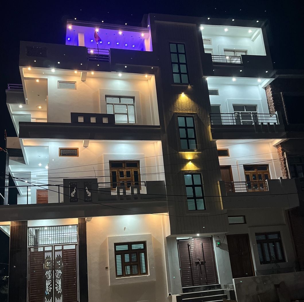 The exterior of the property is showcased at night, highlighting modern architecture and illuminated balconies. Soft lighting emphasizes the building's clean lines and spacious balconies, while front doors and windows create a symmetrical appearance.