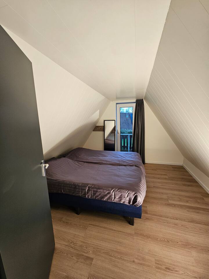 Dormitorio 2 en el primer piso con balcón, donde puedes sentarte con una taza de café al sol y tener vistas al estanque de peces.