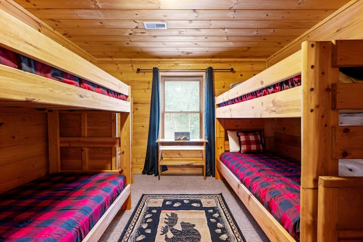 Ხის სახლის ქვედა ნაწილში ორადგილიანი ორსართულიანი საწოლების ორი კომპლექტია, რაც იდეალურია ბავშვებისთვის.
