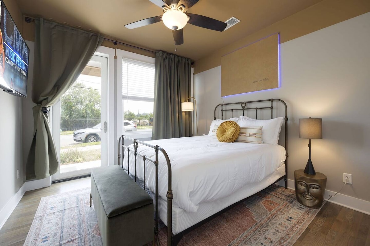 غرفة نوم ثانية تضم سريرًا بحجم كوين مع تلفزيون ذكي بشاشة مسطحة ومفروشات مصممة.