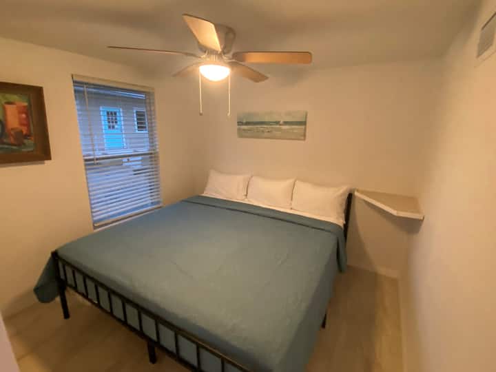 غرفة نوم في الزاوية الشمالية الشرقية مع سرير بمقاس كبير ومروحة سقف للحصول على نسيم وراحة إضافيين