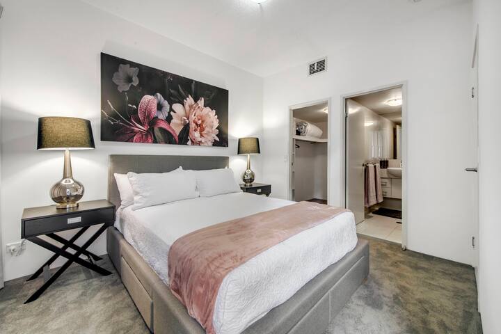 Floral artwork, soft bedding and a private ensuite give the main bedroom at Wild Luxe Beach Front Escape a calm, polished feel.