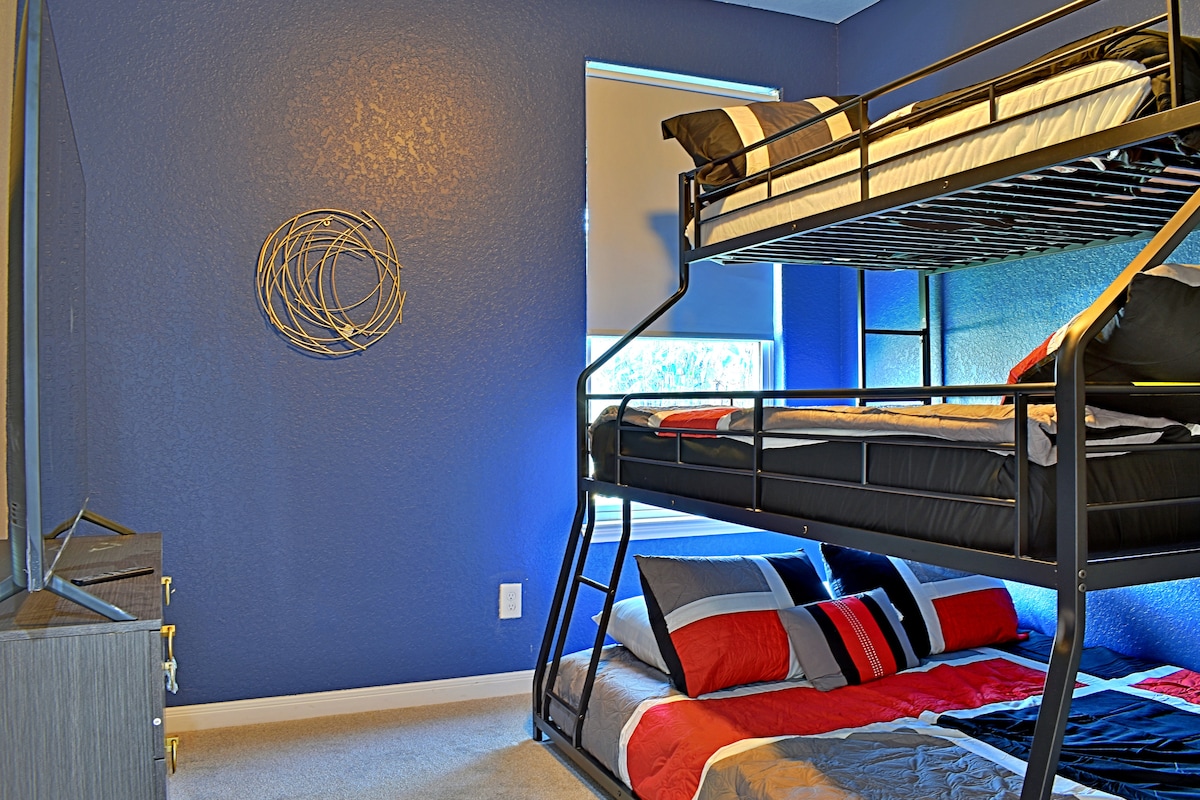 Schlafzimmer mit zwei Einzelbetten über Queensize-Etagenbett und 65-Zoll Samsung 4K-Fernseher