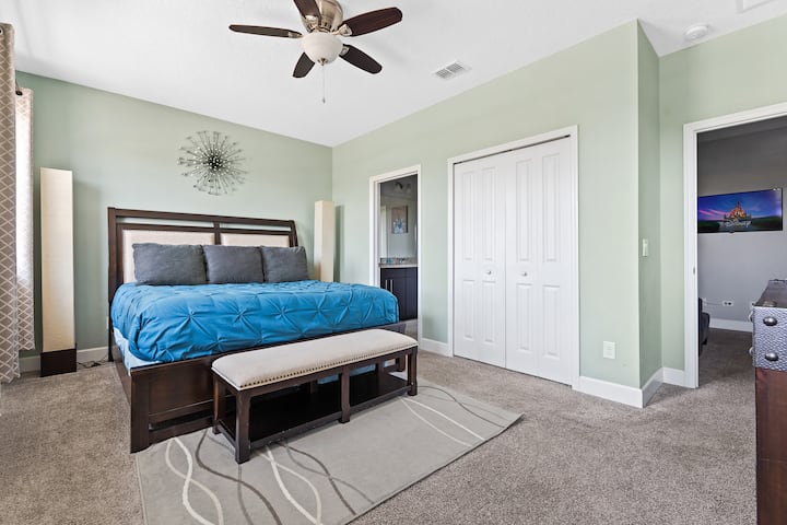 宽敞的加大双人床卧室，设计宜人，绿色、蓝色和灰色，包括一个私人衣柜和一个带双水槽和浴缸套房的浴室。