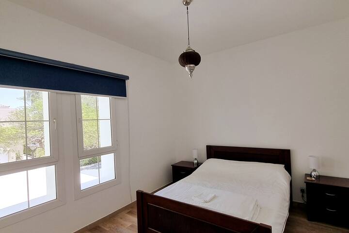 宽敞的第二间卧室，配有双人床、衣柜、床头柜和台灯。