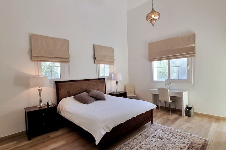 主卧室宽敞，配有加大双人床、梳妆台、步入式衣柜、可俯瞰后花园和套房浴室的阳台。