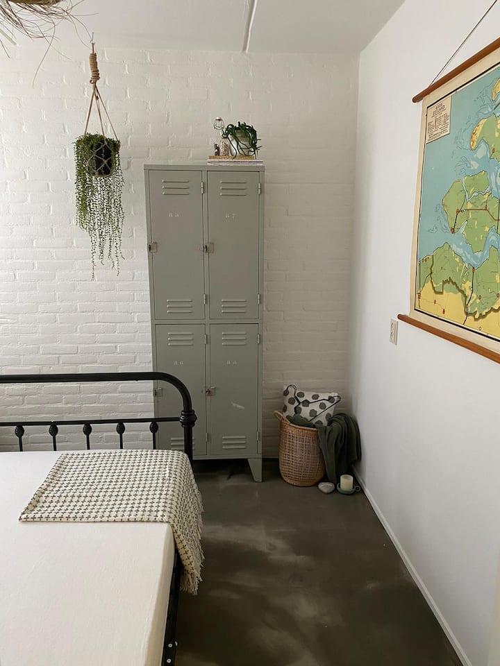De slaapkamer op de begane grond heeft een hele toffe betonlook vloer. De kamer is ingericht in beach stijl. Er staat een fijn tweepersoonsbed. Voor je spullen staat er een locker.  Heb je de vintage kaart van Zeeland gezien?