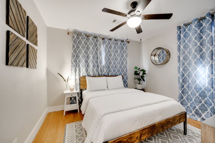 Chambre confortable avec un grand lit, un ventilateur de plafond et des rideaux opaques pour des nuits reposantes.