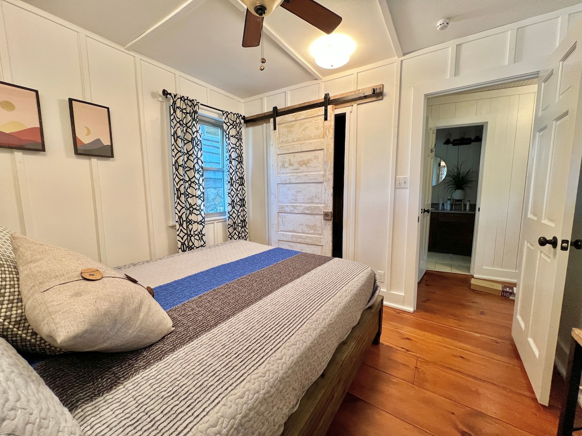 Spavaća soba u brvnari u potkrovlju na glavnom katu s bračnim krevetom. Pogled na jezero.