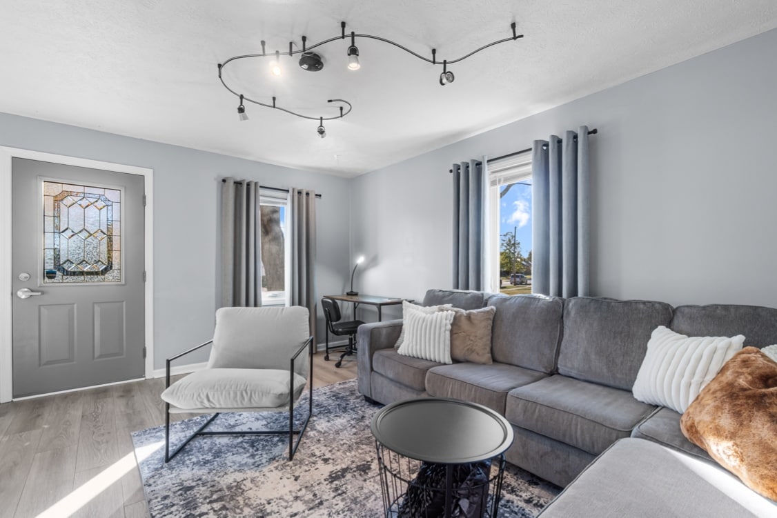 ห้องนั่งเล่นที่อบอุ่นพร้อมโซฟาหรูหมอนนุ่มและสมาร์ททีวี มีพื้นที่ทำงานที่สว่างและสะดวกสบายพร้อมโคมไฟ LED และแสงธรรมชาติที่สมบูรณ์แบบสำหรับการพักผ่อนหรือทำงานให้เสร็จ