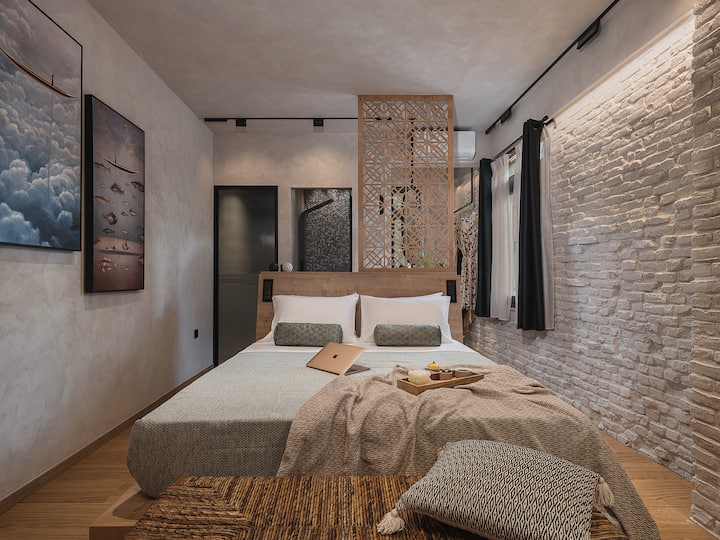 这间迷人的卧室采用外露砖块和定制木质细节，自然纹理与精致设计相得益彰。