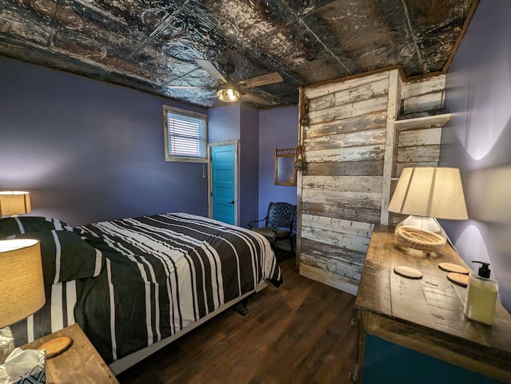 Esta es una bonita habitación grande con una cama tamaño king, un escritorio y una silla para un bonito espacio de trabajo. Este dormitorio tiene mucho carácter.