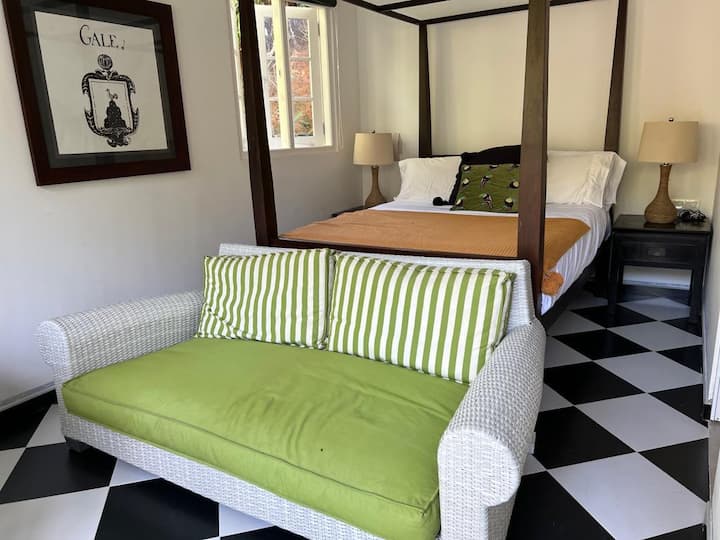 Studio-style room with double bed, lounge area, kitchenette, and veranda doors straight outside with tropical views. 
