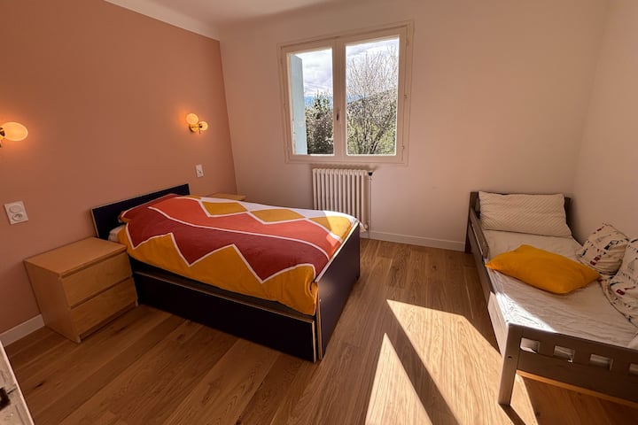 Chambre avec lits superposés gigogne + un lit enfant, vue sur jardin.