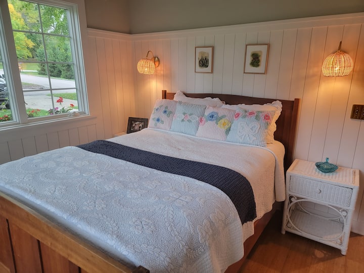 Dhomë gjumi magjepsëse me dekor të stilit vilë, ndriçim të butë dhe një krevat të rehatshëm me pamje nga lagjja e qetë.