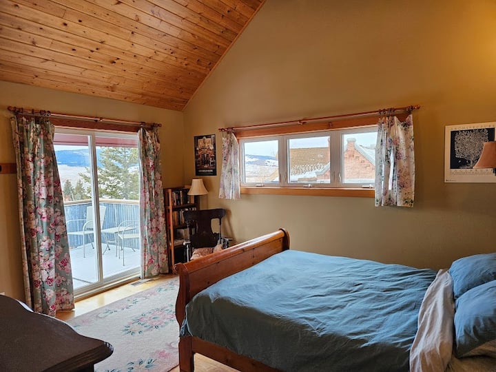 Dormitorio en la planta superior con cama tamaño queen y una terraza fuera de él.