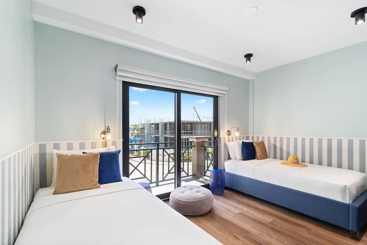 Segundo dormitorio | Descubre la comodidad y la luz natural en el segundo dormitorio de Porta Al Sole, con dos camas individuales y una puerta corrediza que inunda el espacio con sol. 