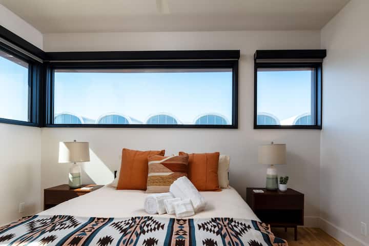 Bedroom 2 features a queen bed and windows on two sides, with room-darkening shades for restful sleep and added privacy.