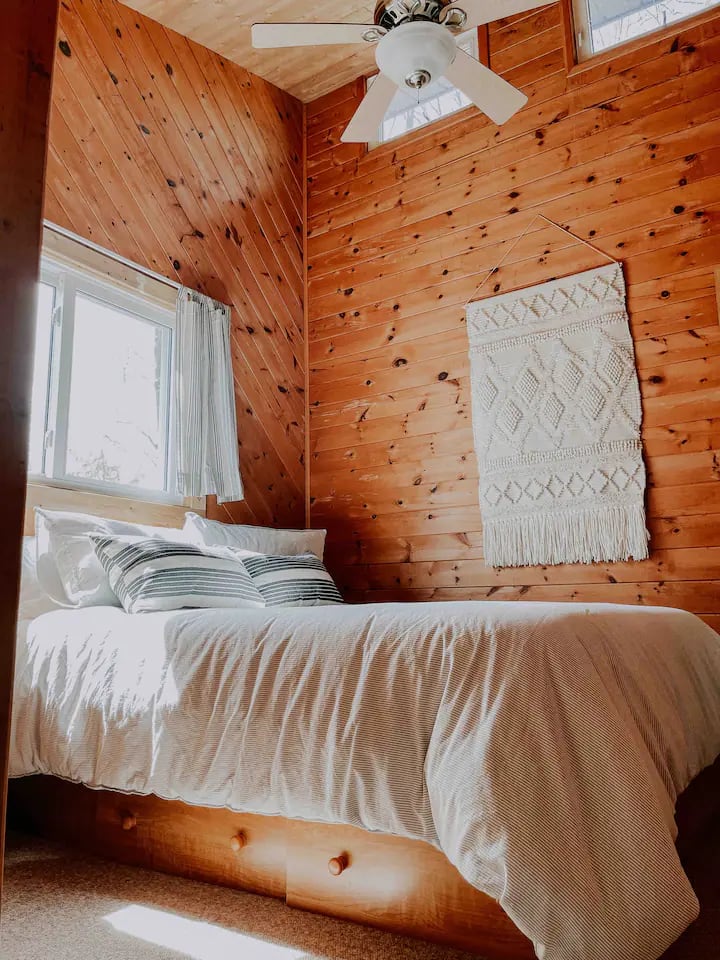 Chumba cha kulala cha kwanza kina kitanda cha kifalme kilicho na sehemu za ndani za kijijini na dirisha kubwa kwa ajili ya machweo ya asubuhi yanayotoka ziwani. 