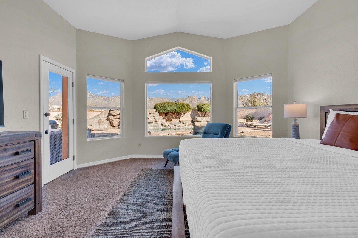 غرفة نوم بسرير كينج مع إطلالة على الفناء الخلفي والجبال.
