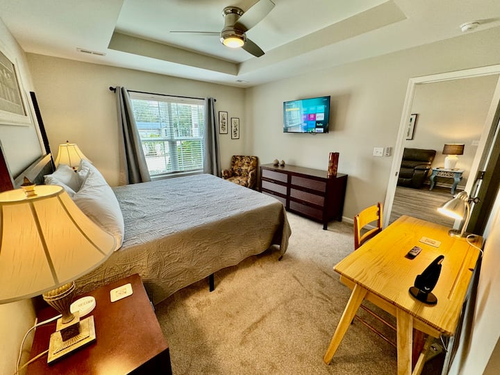 Well equipped suite with night stands, dressers, desk, tv, and ceiling fan.