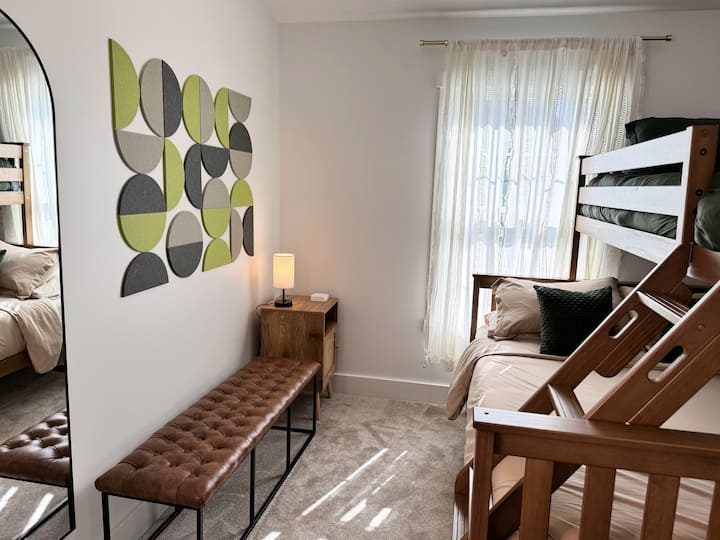 Bunk bedroom has bottom queen bed and top Twin XL bed. Nightstand + power bank for phone charging cords.