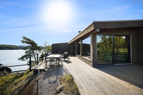 Sunny and modern cabin with its own beach and boat