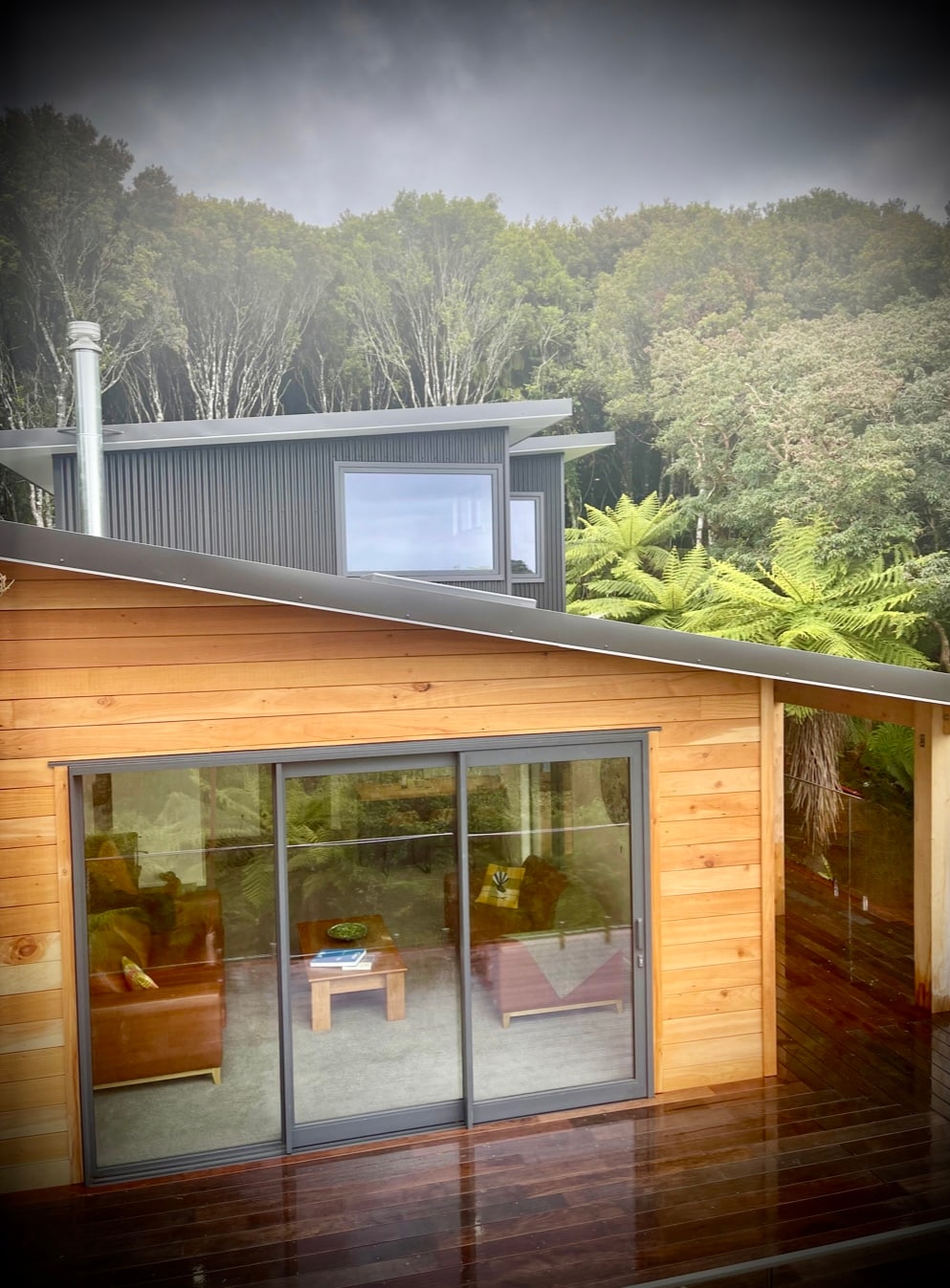 A two-story home features a wooden exterior with large glass doors, revealing a bright interior. The upper level showcases a modern design, set against a backdrop of lush greenery. The surrounding native trees enhance the sense of privacy and seclusion.